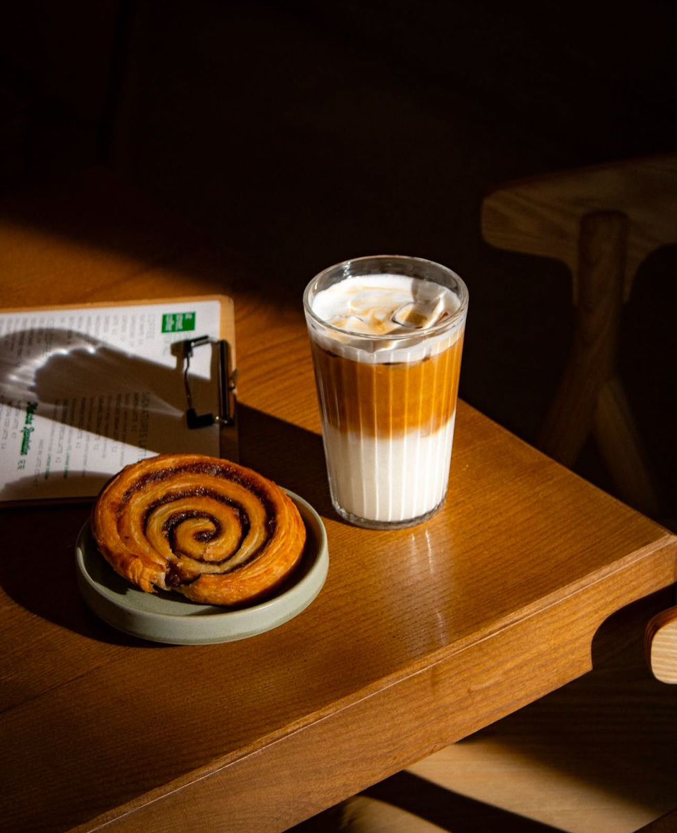 Iced latte and cinnamon swirl pastry on a wooden table
